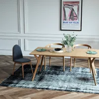Wooden dining table with grey chair and wooden chairs on rug with white wall panels