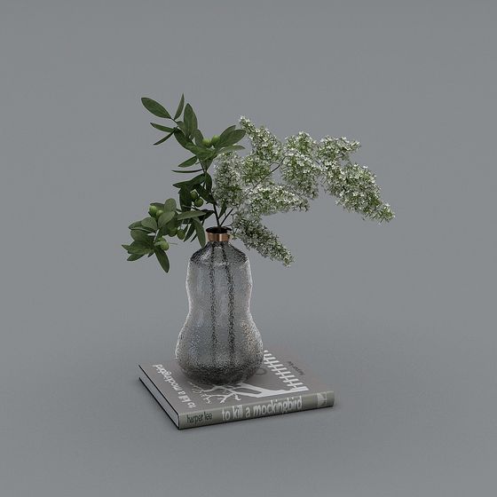 Textured grey glass vase with green leaves and white flowers on book on grey background